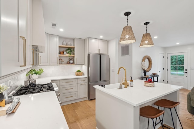521 Carpenter St, Charleston, SC 29412 - kitchen with stainless steel appliances, open shelves, light countertops, light wood-style floors, and decorative backsplash