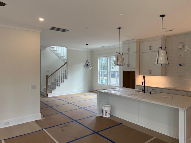 kitchen with decorative light fixtures, sink, white cabinets, ornamental molding, and light stone countertops