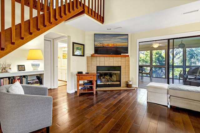 living room featuring dark wood-type flooring and a tiled fireplace