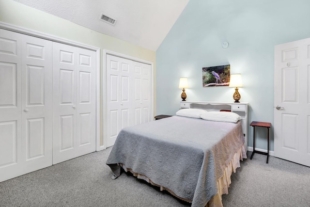 bedroom with multiple closets, light colored carpet, and high vaulted ceiling