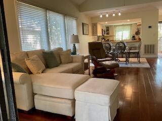 living room featuring rail lighting, lofted ceiling, and dark hardwood / wood-style floors