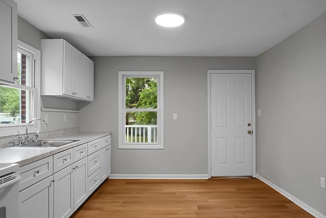 5056 Piedmont Ave, North Charleston, SC 29406 - kitchen featuring a sink, light wood finished floors, light countertops, and white cabinetry