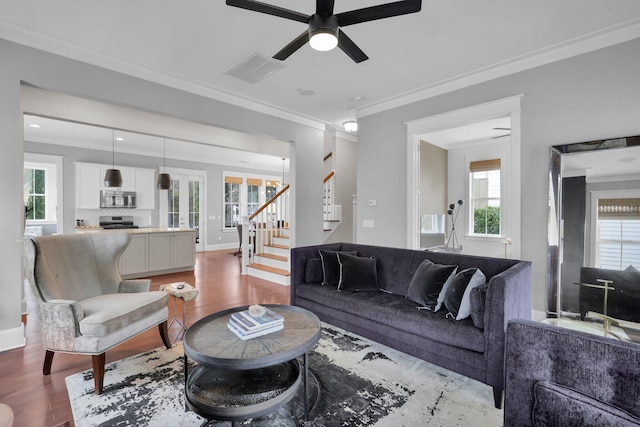 living room with a ceiling fan, crown molding, stairway, and wood finished floors