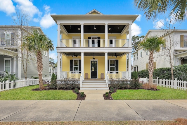 view of front facade with a porch, fence, a balcony, and a ceiling fan