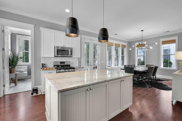 kitchen featuring stainless steel appliances, dark wood-type flooring, a kitchen island, and ornamental molding