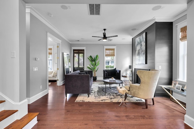 living area featuring visible vents, crown molding, baseboards, and wood finished floors