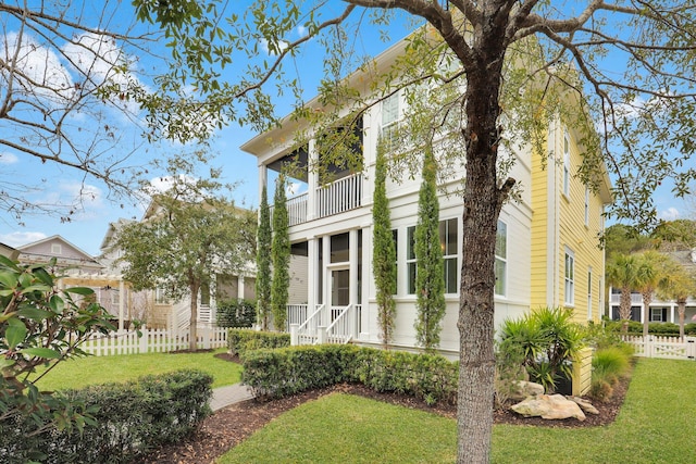 view of property exterior featuring a yard, fence, and a balcony