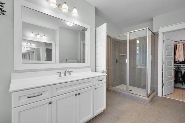 bathroom with a stall shower, tile patterned flooring, a walk in closet, and vanity