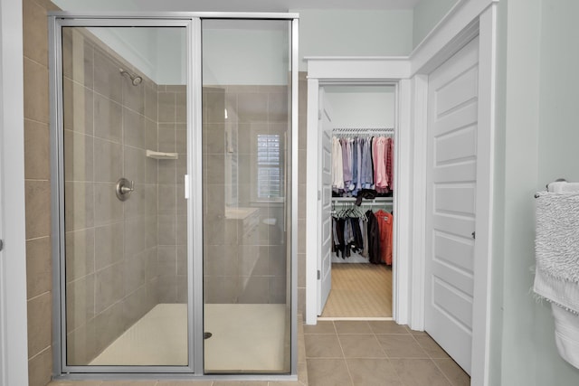 bathroom with a stall shower, tile patterned flooring, and a walk in closet