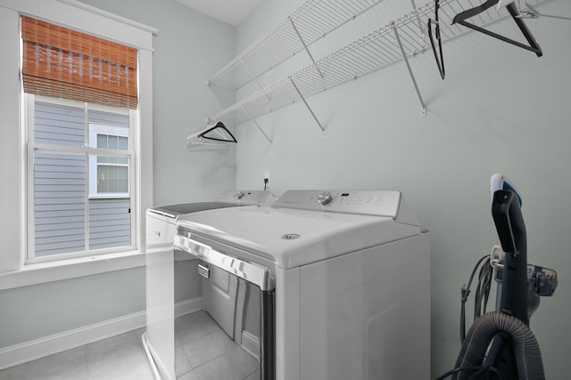 washroom featuring laundry area, baseboards, washing machine and clothes dryer, and light tile patterned floors