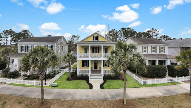 view of front of home featuring covered porch, fence, a balcony, and a front lawn