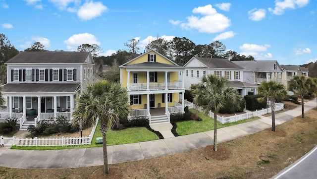 view of front of property featuring a fenced front yard, covered porch, a balcony, and a front lawn