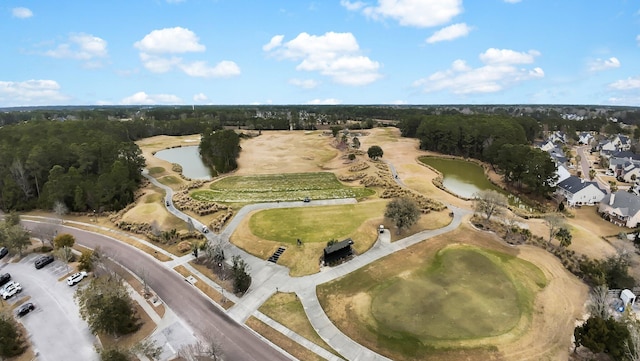 drone / aerial view with view of golf course, a water view, and a wooded view