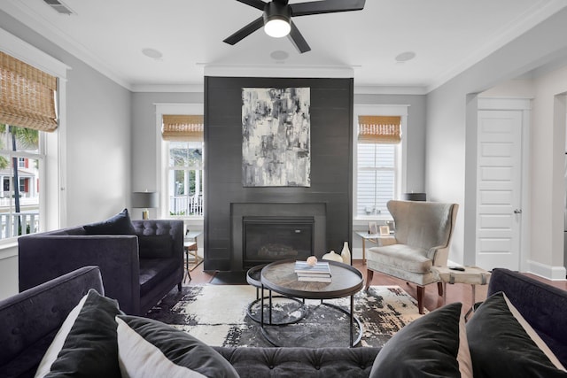 living room featuring ornamental molding, a large fireplace, visible vents, and wood finished floors