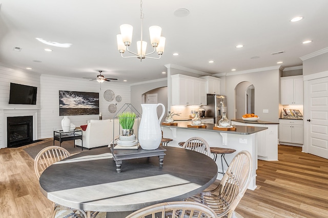 dining space featuring light hardwood / wood-style floors, sink, ornamental molding, and ceiling fan with notable chandelier