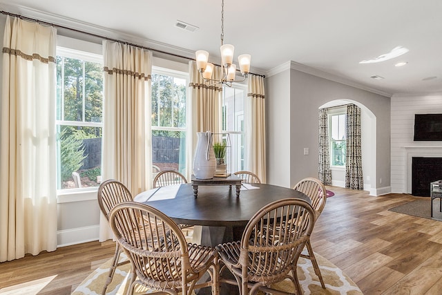 dining area with a healthy amount of sunlight, a notable chandelier, light hardwood / wood-style floors, and crown molding