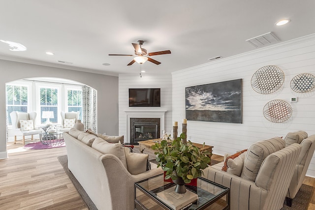 living room featuring wooden walls, light wood-type flooring, and ceiling fan