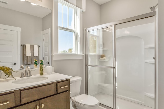 bathroom featuring a shower with door, a healthy amount of sunlight, toilet, and vanity