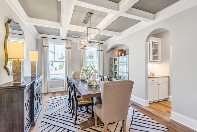 dining room with coffered ceiling, light wood-type flooring, and crown molding