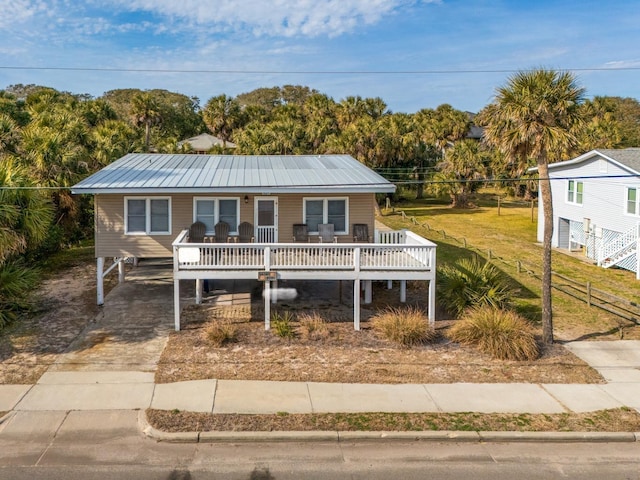 view of front facade featuring a wooden deck, a front yard, and a carport