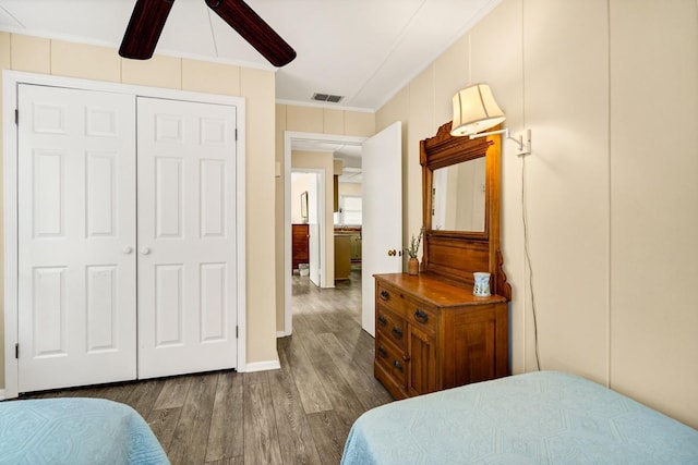 bedroom featuring hardwood / wood-style flooring, ceiling fan, ornamental molding, and a closet