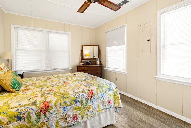 bedroom featuring crown molding, ceiling fan, electric panel, and hardwood / wood-style floors