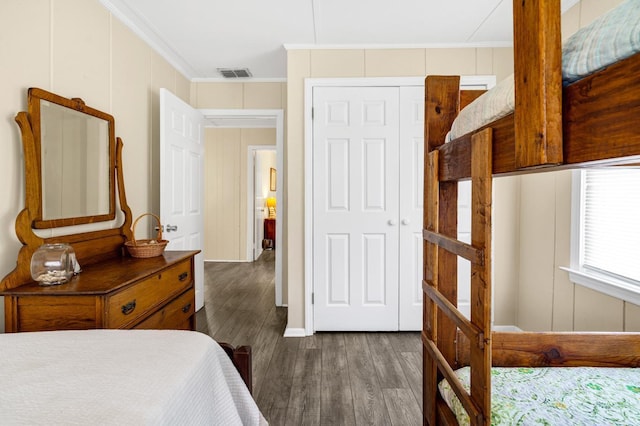 bedroom featuring dark wood-type flooring, ornamental molding, and a closet