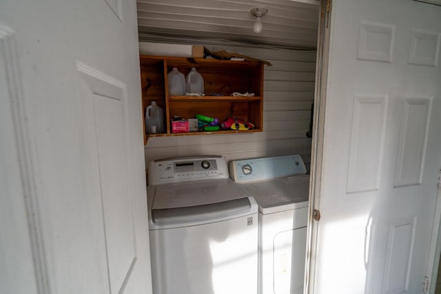 laundry area with separate washer and dryer and wood walls