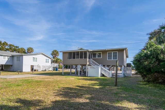 rear view of house with a lawn and a sunroom