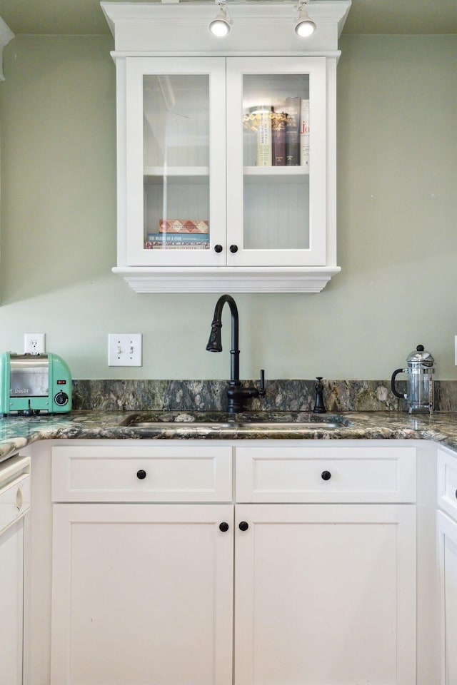 bar with dishwasher, sink, dark stone countertops, and white cabinets