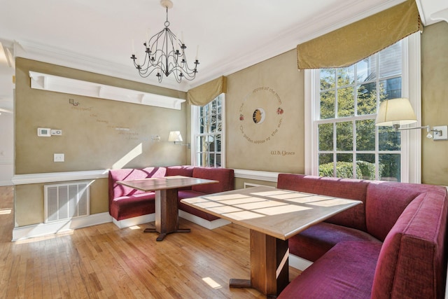 dining room with breakfast area, ornamental molding, a chandelier, and light hardwood / wood-style flooring