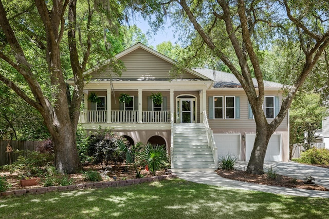 beach home featuring fence, concrete driveway, an attached garage, stairway, and a porch