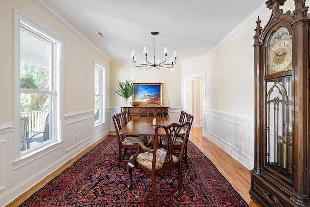 dining area featuring visible vents, light wood-style flooring, crown molding, and a chandelier