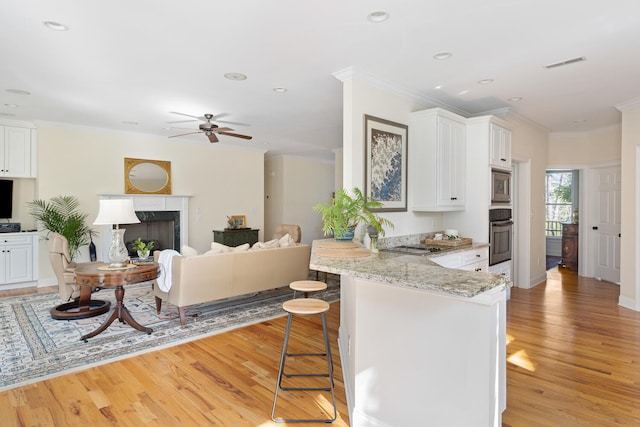 kitchen featuring visible vents, a breakfast bar area, ceiling fan, light wood-type flooring, and appliances with stainless steel finishes