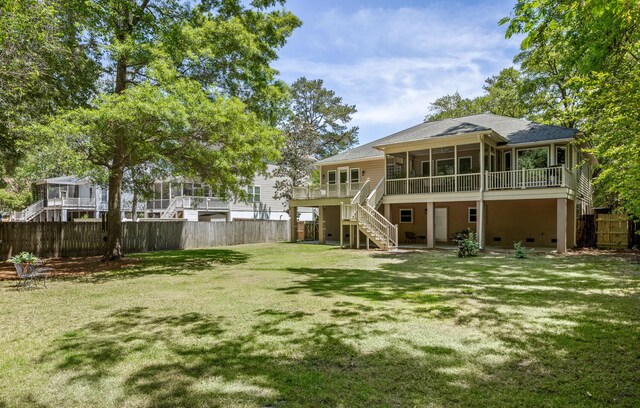 rear view of house featuring a fenced backyard, roof with shingles, a sunroom, a lawn, and stairway