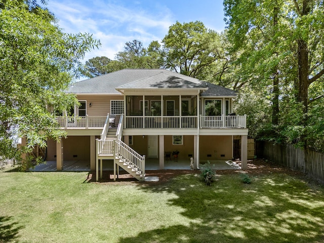 rear view of property featuring fence, a sunroom, a patio area, a yard, and stairway