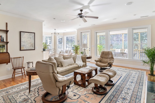 living room with crown molding, visible vents, baseboards, a ceiling fan, and light wood-style flooring