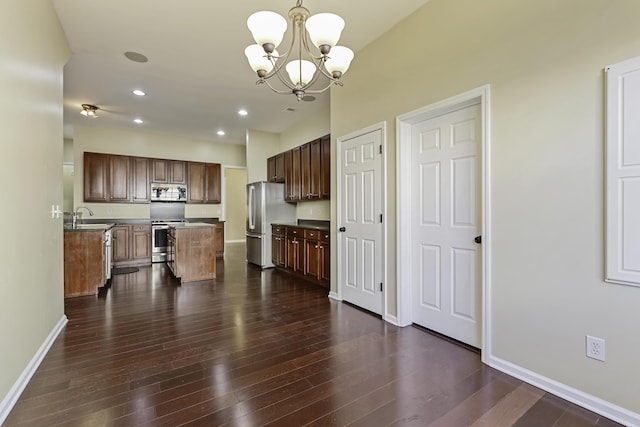 kitchen featuring appliances with stainless steel finishes, dark hardwood / wood-style floors, a center island, and hanging light fixtures