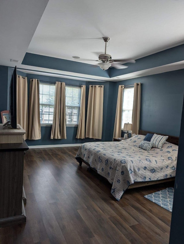 bedroom featuring dark wood-type flooring, ceiling fan, and a tray ceiling