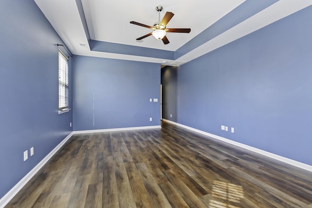 unfurnished room featuring a tray ceiling, dark wood-type flooring, and ceiling fan