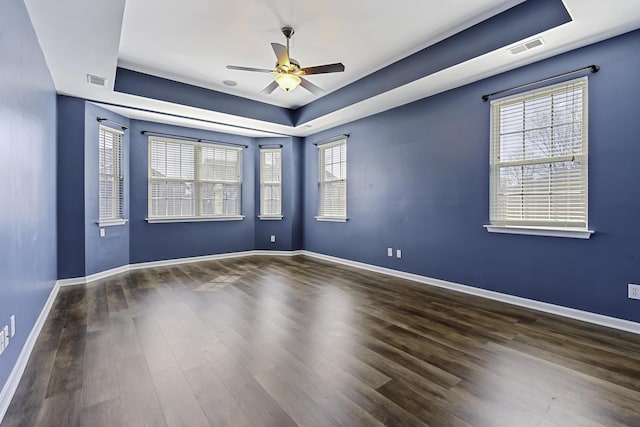 unfurnished room with a tray ceiling, dark wood-type flooring, and ceiling fan