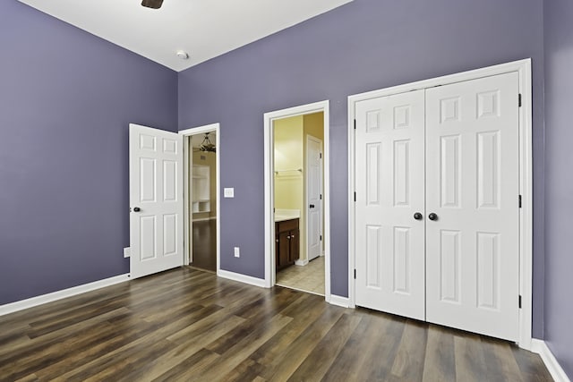 unfurnished bedroom with ensuite bath, dark wood-type flooring, and a closet