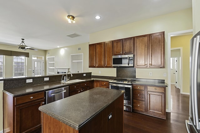 kitchen featuring dark hardwood / wood-style floors, sink, a center island, kitchen peninsula, and stainless steel appliances