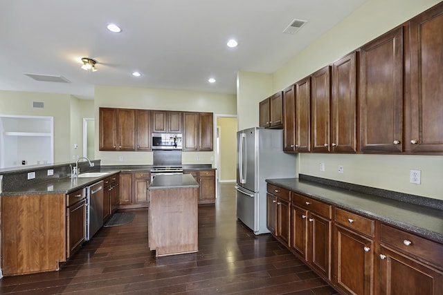 kitchen with sink, dark wood-type flooring, appliances with stainless steel finishes, a kitchen island, and kitchen peninsula