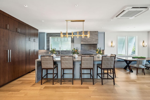 kitchen with dark brown cabinetry, light hardwood / wood-style floors, a kitchen breakfast bar, a center island, and decorative backsplash