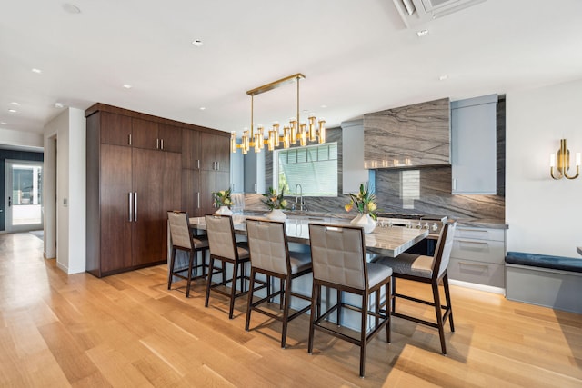 dining area with light wood-type flooring, sink, and an inviting chandelier