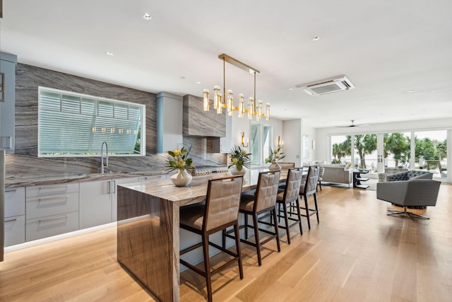 kitchen with a kitchen island, light wood-type flooring, decorative light fixtures, and ceiling fan with notable chandelier