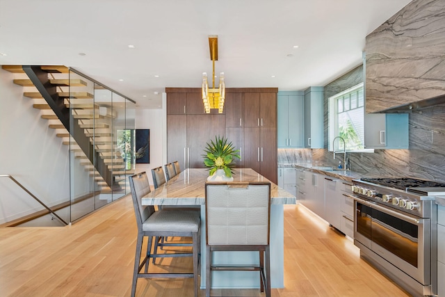 kitchen with light hardwood / wood-style floors, range with two ovens, pendant lighting, and a kitchen island