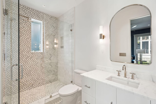 bathroom featuring toilet, vanity, and a shower with door