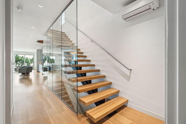 stairway with hardwood / wood-style floors and an AC wall unit